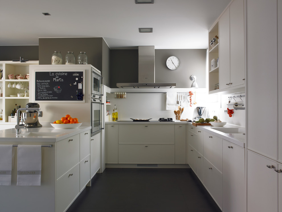 Modelo de cocina comedor rectangular actual grande con fregadero integrado, puertas de armario blancas, electrodomésticos de acero inoxidable y península