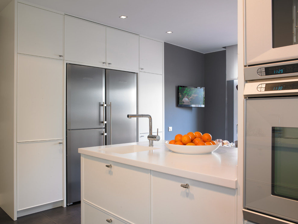 Imagen de cocina comedor contemporánea grande con fregadero integrado, puertas de armario blancas, electrodomésticos de acero inoxidable y península