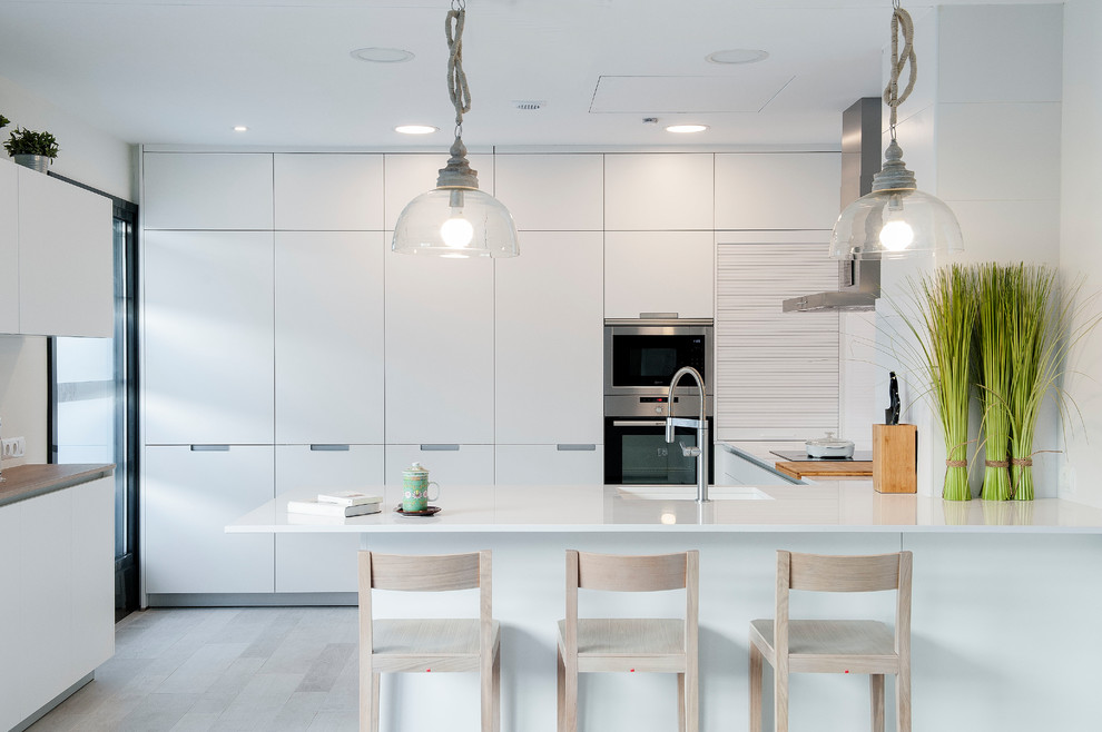 Idéer för att renovera ett funkis kök, med en enkel diskho, släta luckor, vita skåp, rostfria vitvaror, ljust trägolv, en halv köksö och beiget golv