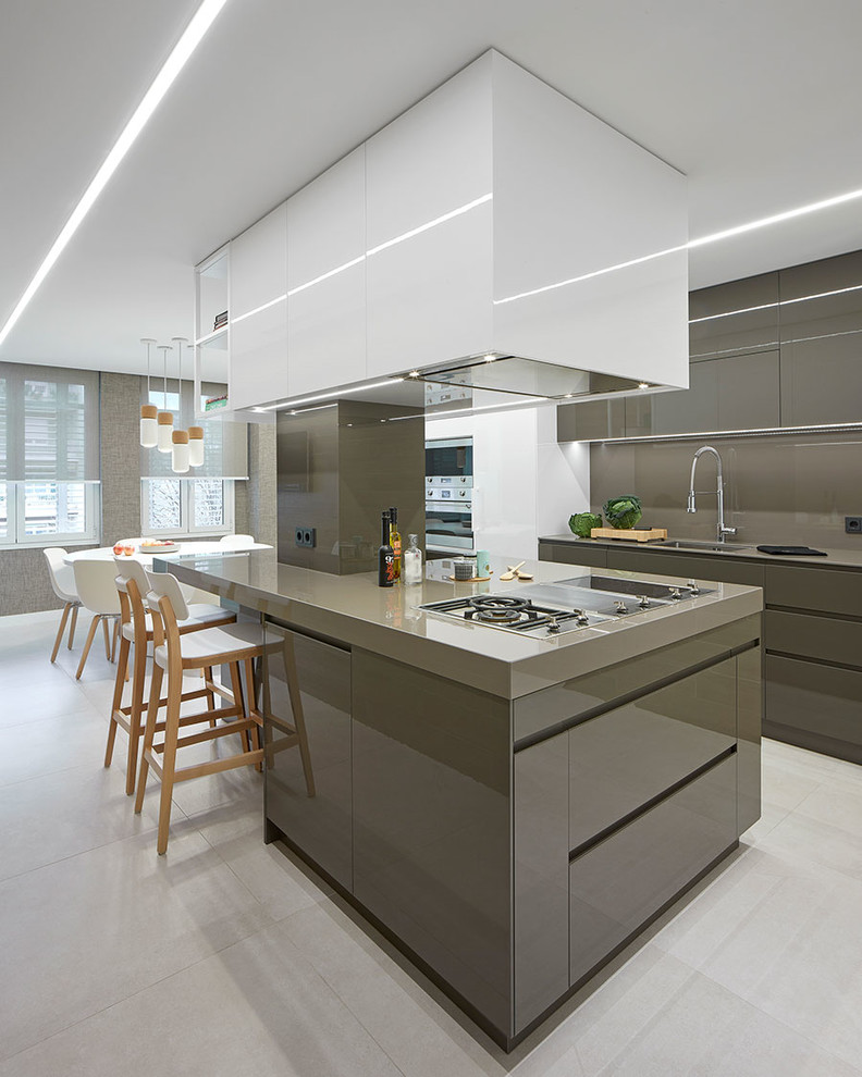 Photo of a contemporary l-shaped kitchen/diner in Barcelona with a submerged sink, flat-panel cabinets, grey cabinets, grey splashback, integrated appliances, an island, grey floors and grey worktops.