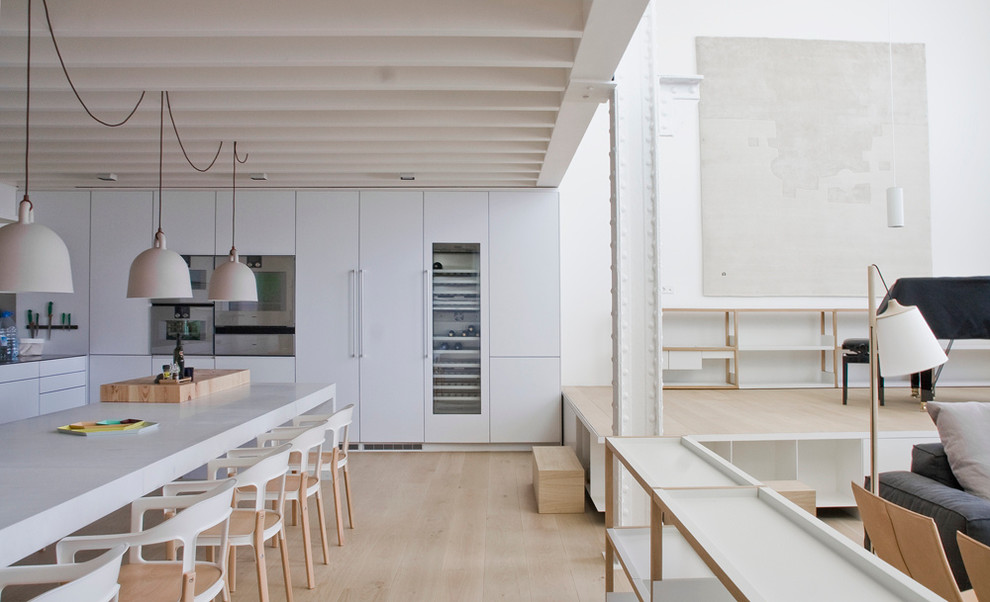 Foto på ett stort skandinaviskt kök, med släta luckor, vita skåp, integrerade vitvaror, ljust trägolv och en köksö