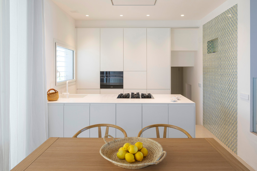 This is an example of a medium sized mediterranean open plan kitchen in Other with an integrated sink, flat-panel cabinets, white cabinets, black appliances, concrete flooring, a breakfast bar, grey floors and white worktops.