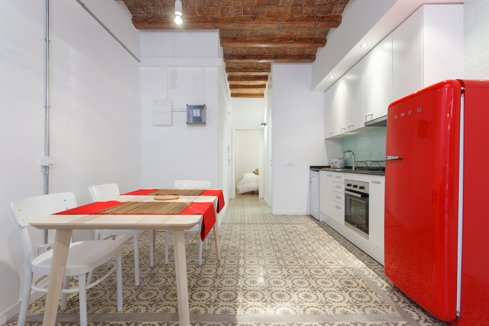 This is an example of a medium sized urban single-wall kitchen/diner in Barcelona with flat-panel cabinets, white cabinets, metro tiled splashback, coloured appliances, ceramic flooring and no island.