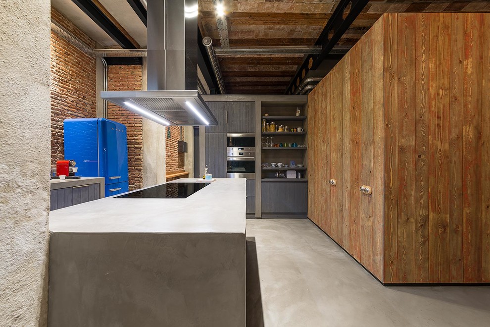 Offene, Zweizeilige, Große Industrial Küche mit Betonarbeitsplatte, bunten Elektrogeräten, Betonboden und Halbinsel in Barcelona