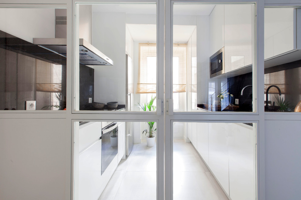 Идея дизайна: отдельная, параллельная кухня среднего размера в современном стиле с плоскими фасадами, белыми фасадами, черным фартуком и белым полом без острова