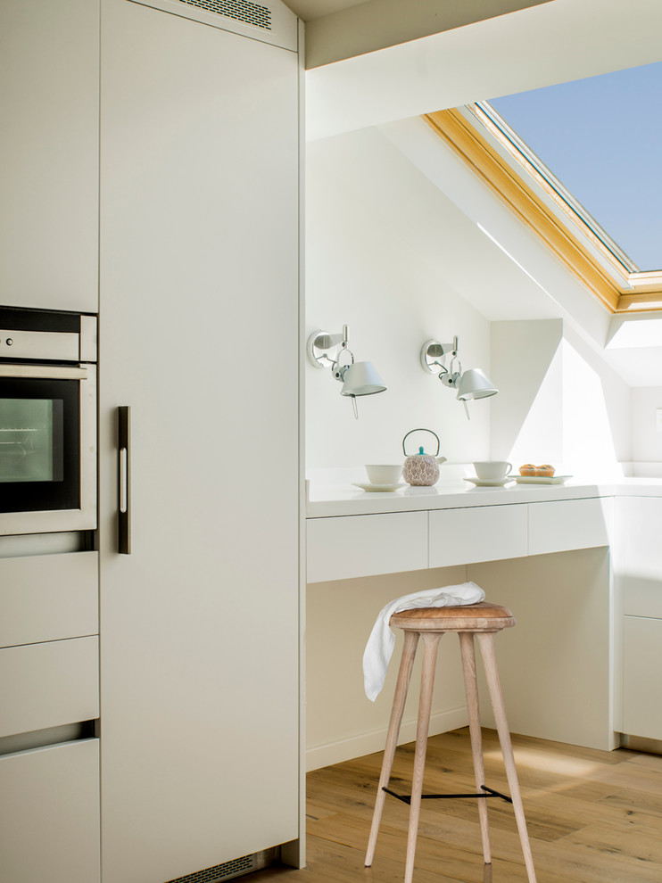 バルセロナにある低価格の小さなコンテンポラリースタイルのおしゃれなキッチン (フラットパネル扉のキャビネット、白いキャビネット、淡色無垢フローリング、白いキッチンパネル、シルバーの調理設備、アイランドなし) の写真