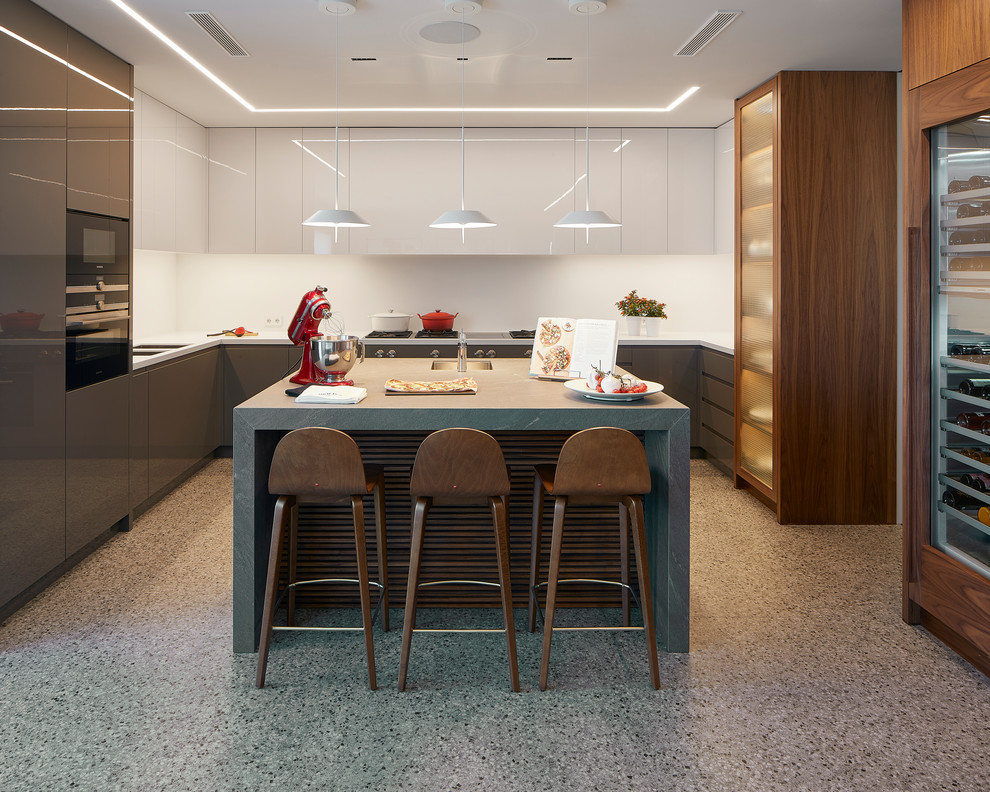 Trendy u-shaped gray floor kitchen photo in Barcelona with an undermount sink, flat-panel cabinets, gray cabinets, white backsplash, an island and white countertops