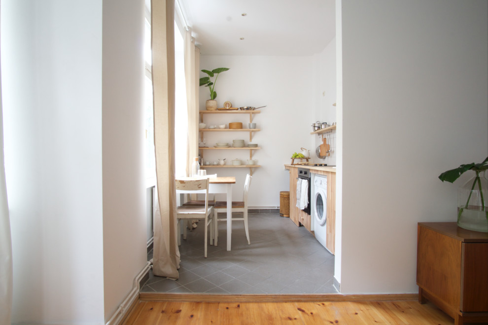 Foto på ett avskilt, stort minimalistiskt linjärt kök, med en nedsänkt diskho, släta luckor, skåp i mellenmörkt trä, träbänkskiva, vitt stänkskydd, glaspanel som stänkskydd, rostfria vitvaror, ljust trägolv och brunt golv