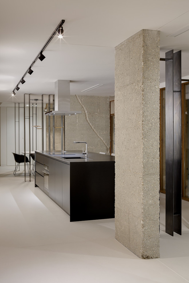 Minimalist concrete floor and gray floor kitchen photo in Alicante-Costa Blanca with flat-panel cabinets, black cabinets, an island, black countertops, an integrated sink and black appliances