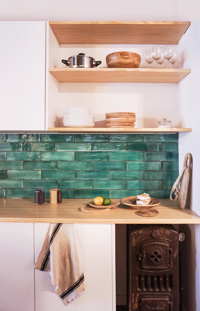 Bild på ett mellanstort medelhavsstil kök, med luckor med infälld panel, vita skåp, träbänkskiva, grönt stänkskydd, stänkskydd i keramik, mellanmörkt trägolv och en köksö