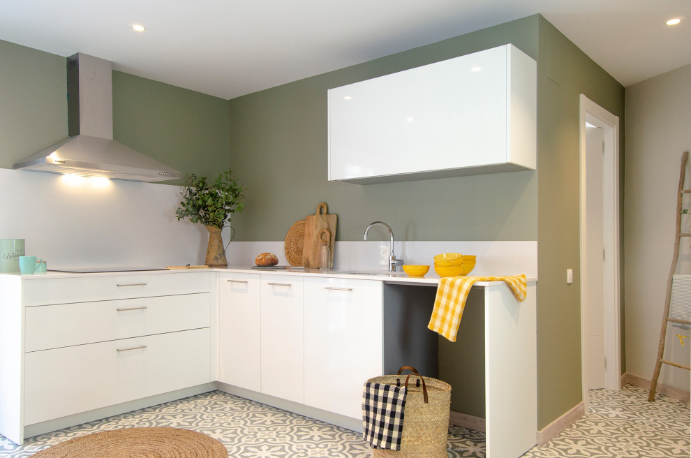 Small contemporary l-shaped kitchen in Barcelona with a submerged sink, flat-panel cabinets, white cabinets, white splashback, stainless steel appliances, no island, multi-coloured floors and white worktops.