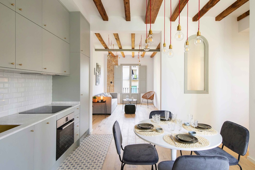 На фото: прямая кухня-гостиная в скандинавском стиле с плоскими фасадами, серыми фасадами, белым фартуком, фартуком из плитки кабанчик, разноцветным полом и белой столешницей без острова