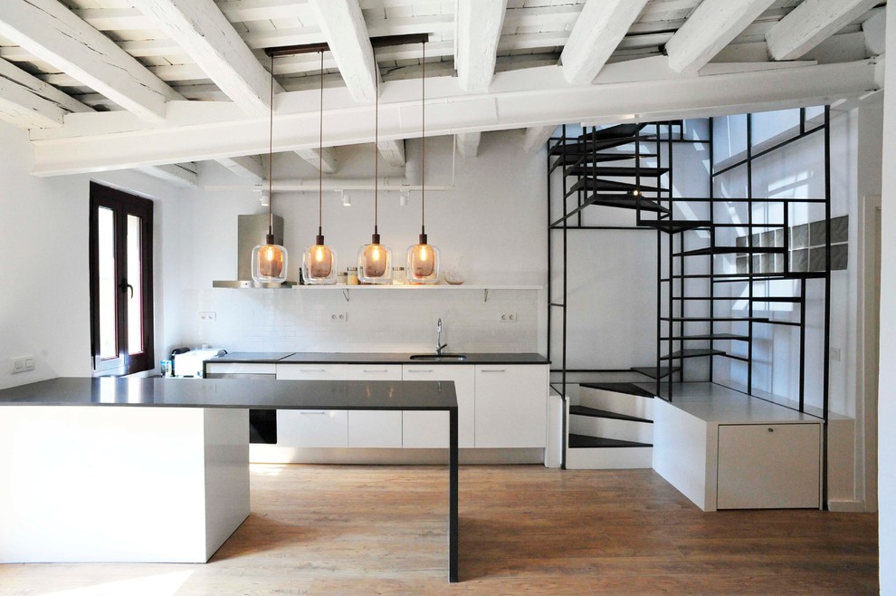 Enclosed kitchen - mid-sized contemporary galley medium tone wood floor enclosed kitchen idea in Barcelona with an undermount sink, flat-panel cabinets, white cabinets, white backsplash, stainless steel appliances and a peninsula