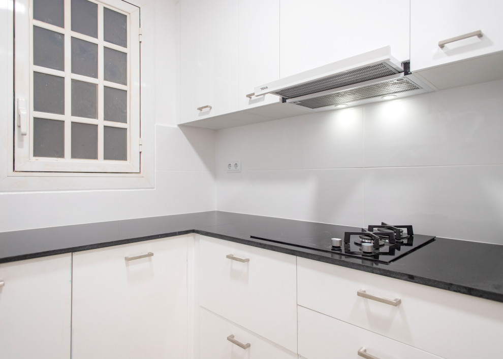 Bild på ett avskilt, mellanstort funkis svart svart u-kök, med vita skåp, vitt stänkskydd, stänkskydd i keramik, rostfria vitvaror och en dubbel diskho