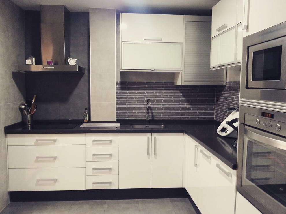 Modern inredning av ett avskilt, mellanstort svart svart l-kök, med en undermonterad diskho, bänkskiva i kvarts, rostfria vitvaror, klinkergolv i porslin och grått golv