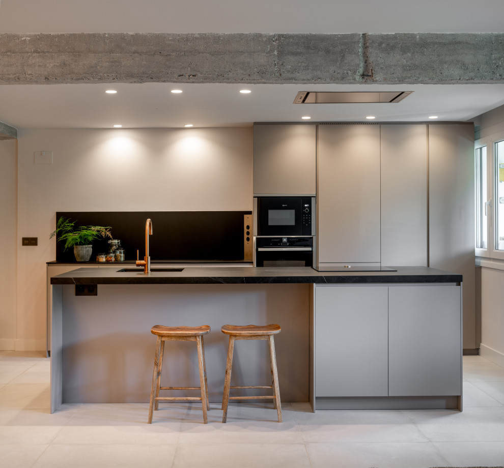 Foto di una cucina moderna con lavello sottopiano, ante lisce, ante grigie, elettrodomestici in acciaio inossidabile, pavimento grigio e top nero