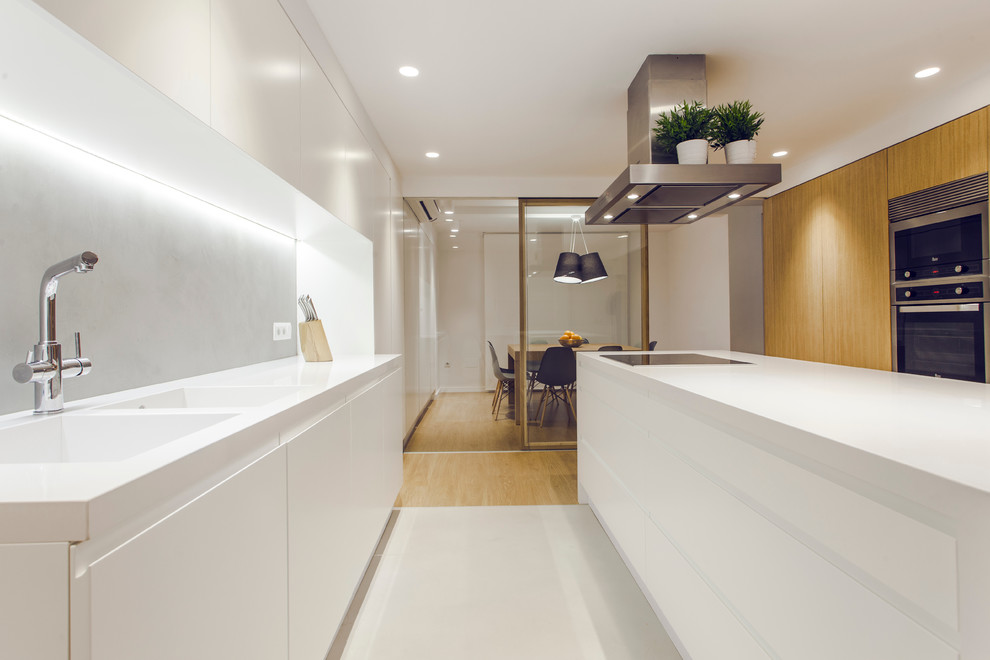 Idéer för ett mellanstort minimalistiskt linjärt kök med öppen planlösning, med en dubbel diskho, släta luckor, vita skåp, rostfria vitvaror och en köksö