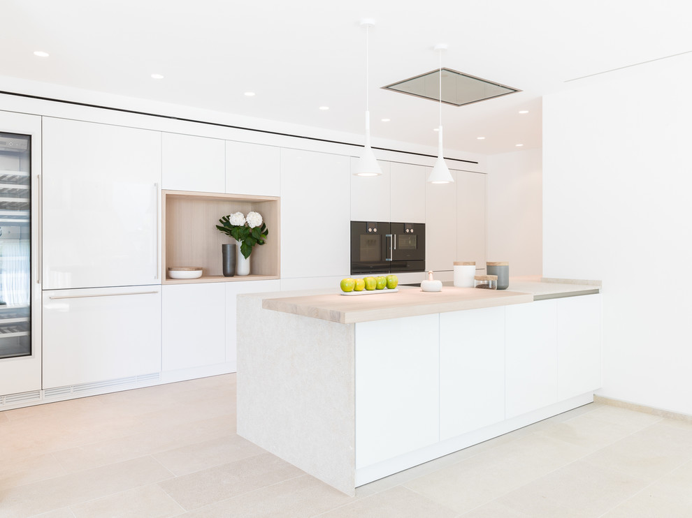 Imagen de cocina lineal contemporánea grande abierta con armarios con paneles lisos, puertas de armario blancas, electrodomésticos negros y península