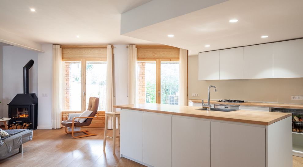 Inspiration for a small contemporary galley open plan kitchen in Other with a single-bowl sink, flat-panel cabinets, white cabinets, wood worktops, white splashback, stainless steel appliances, medium hardwood flooring, an island, brown floors and brown worktops.