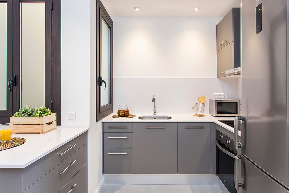 Foto på ett litet funkis kök, med en undermonterad diskho, släta luckor, grå skåp, bänkskiva i kvarts, vitt stänkskydd och rostfria vitvaror