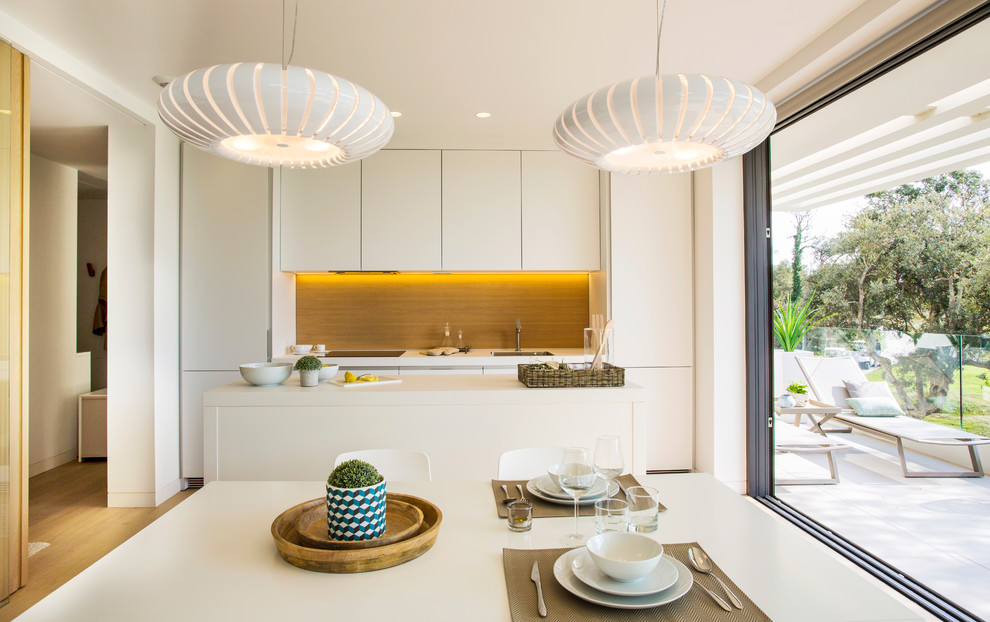Foto di una cucina minimal di medie dimensioni con lavello sottopiano, ante lisce, ante bianche, paraspruzzi marrone, elettrodomestici da incasso e top bianco