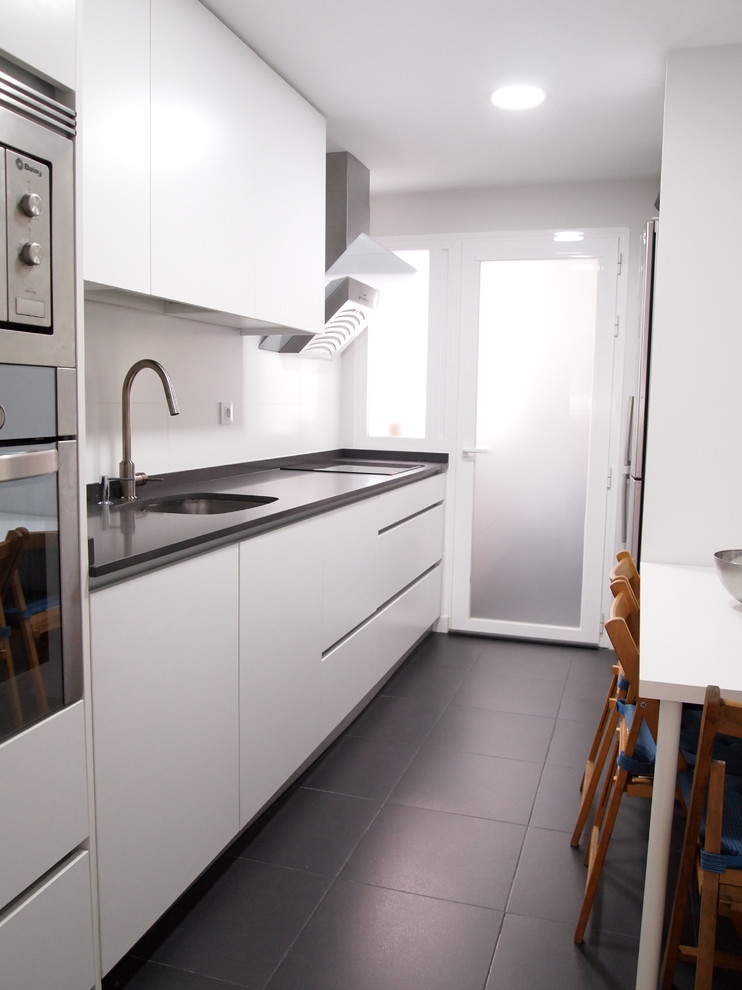 Immagine di una cucina lineare design con lavello sottopiano, ante lisce, ante bianche, top in quarzo composito, paraspruzzi bianco, pavimento con piastrelle in ceramica, pavimento grigio e top grigio