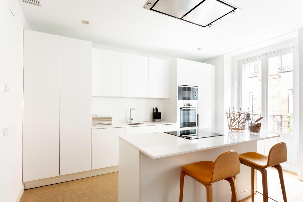 Bild på ett mellanstort funkis vit linjärt vitt kök, med en undermonterad diskho, släta luckor, vita skåp, bänkskiva i kvarts, vitt stänkskydd, rostfria vitvaror, en köksö och beiget golv
