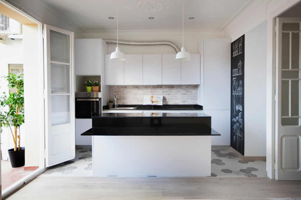 Inspiration for a medium sized contemporary galley open plan kitchen in Barcelona with a single-bowl sink, flat-panel cabinets, white cabinets, granite worktops, beige splashback, stone tiled splashback, stainless steel appliances, light hardwood flooring and an island.