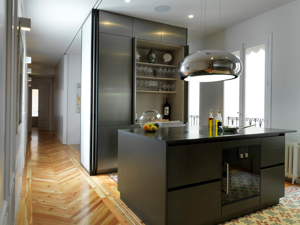 Inspiration för ett litet funkis svart linjärt svart kök med öppen planlösning, med släta luckor, skåp i rostfritt stål, svarta vitvaror, en köksö, marmorbänkskiva, grått stänkskydd, klinkergolv i keramik och flerfärgat golv