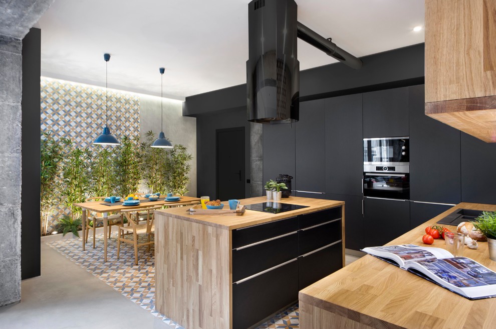 Eat-in kitchen - mid-sized industrial single-wall ceramic tile and multicolored floor eat-in kitchen idea in Barcelona with flat-panel cabinets, black cabinets, wood countertops, black appliances, an island and brown backsplash