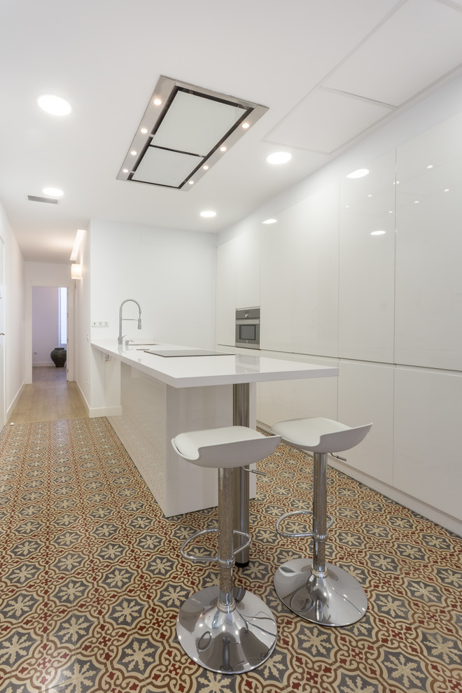 Moderne Küche mit Unterbauwaschbecken, flächenbündigen Schrankfronten, weißen Schränken, Kücheninsel, buntem Boden und weißer Arbeitsplatte in Sevilla