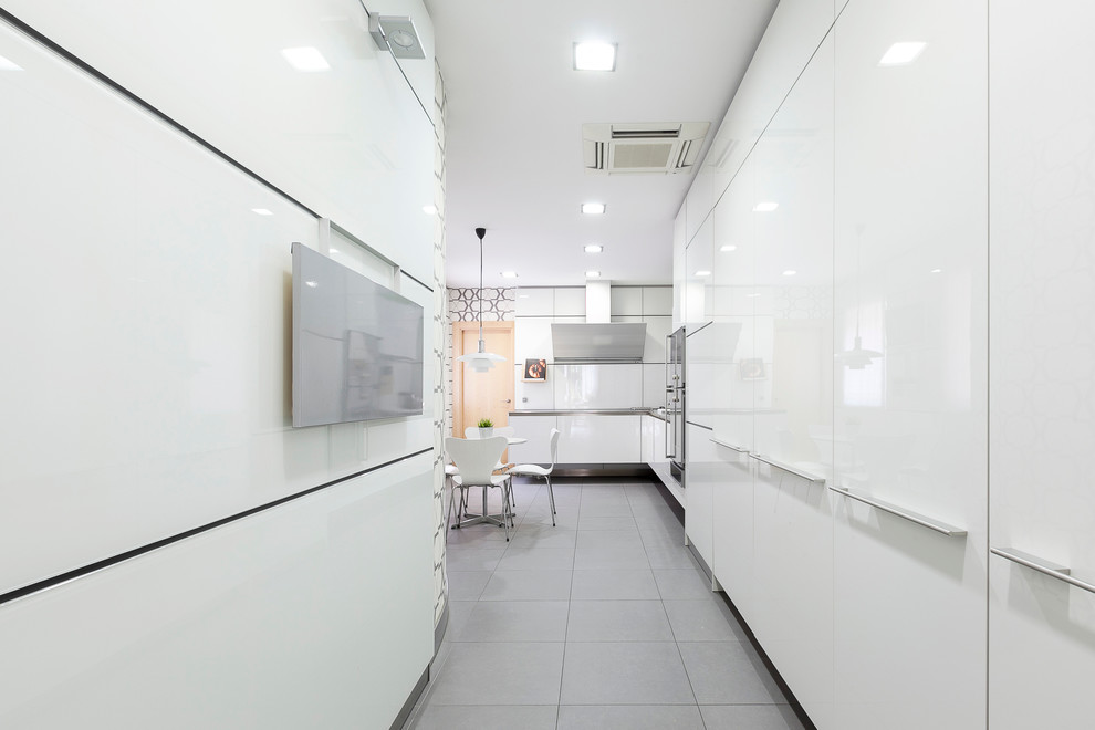 Large contemporary l-shaped kitchen/diner in Madrid with a single-bowl sink, flat-panel cabinets, white cabinets, ceramic flooring and no island.
