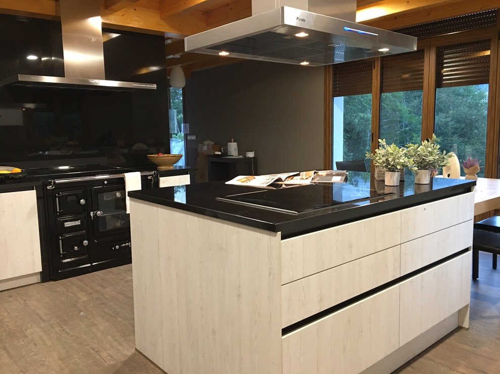 This is an example of a large contemporary l-shaped kitchen/diner in Other with a submerged sink, flat-panel cabinets, light wood cabinets, granite worktops, metal splashback, black appliances, ceramic flooring, an island and brown floors.