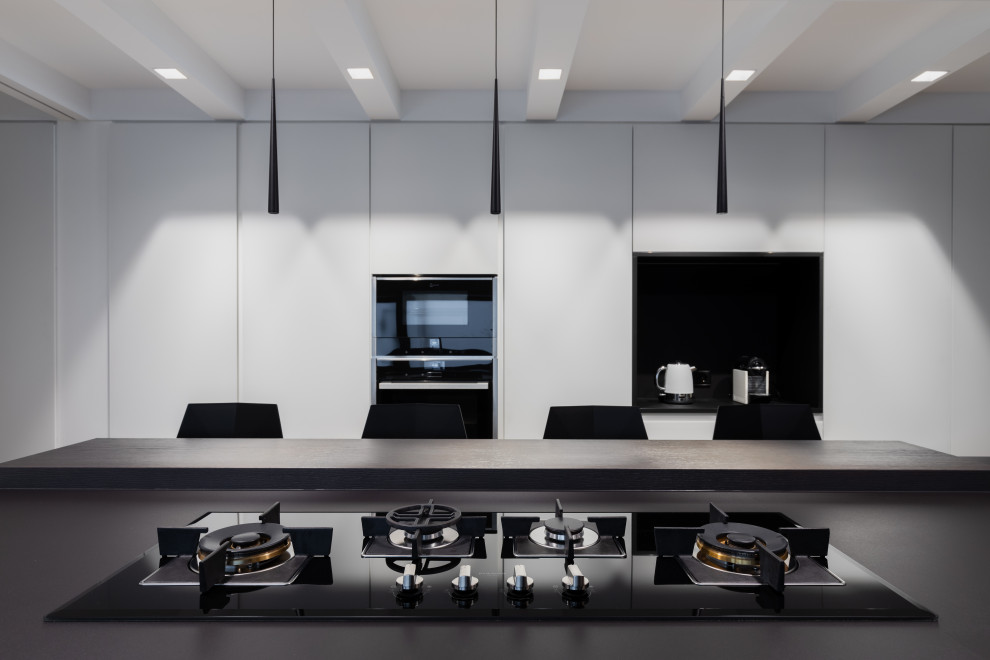 Esempio di una grande cucina minimal con elettrodomestici neri, pavimento in legno massello medio e top nero