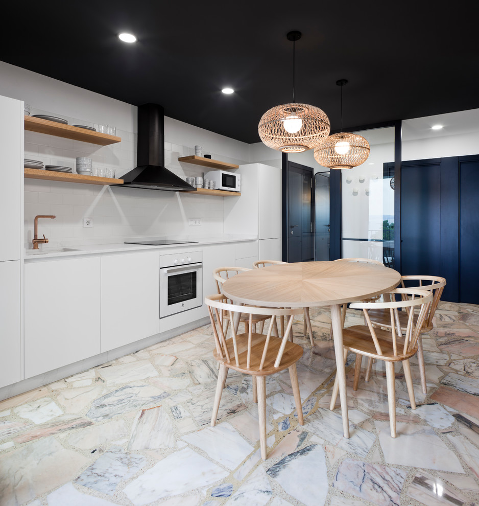 Contemporary single-wall kitchen/diner in Other with an integrated sink, flat-panel cabinets, white cabinets, white splashback, white appliances, marble flooring, no island, white worktops and beige floors.