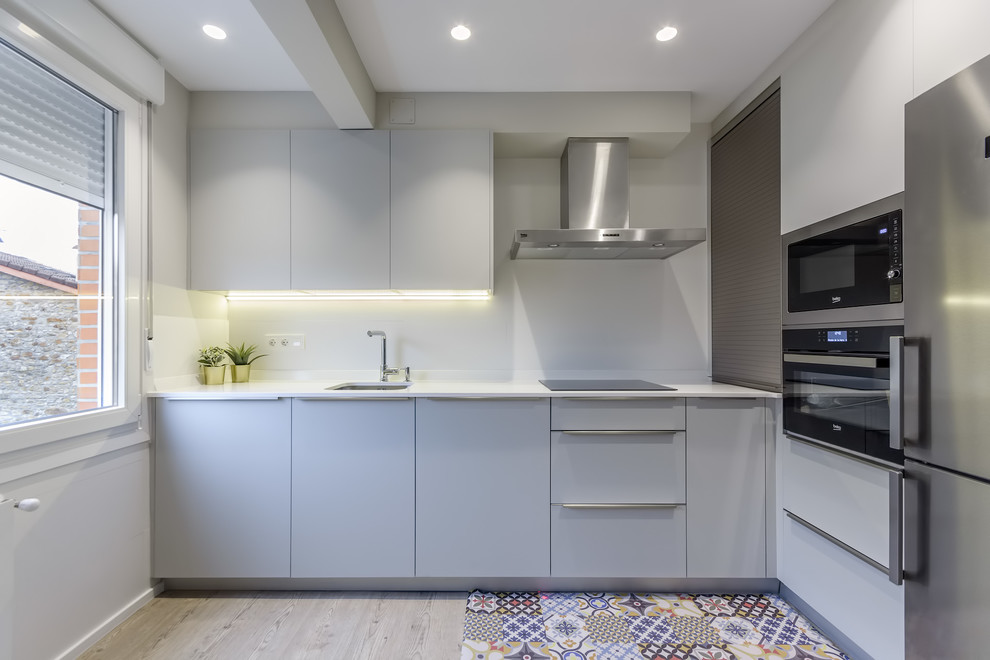 Trendy multicolored floor kitchen photo in Bilbao with an undermount sink, flat-panel cabinets, white backsplash, no island, white countertops, gray cabinets and stainless steel appliances