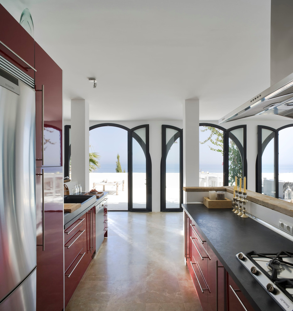 На фото: большая параллельная кухня-гостиная в средиземноморском стиле с с полувстраиваемой мойкой (с передним бортиком), плоскими фасадами, красными фасадами и техникой из нержавеющей стали без острова