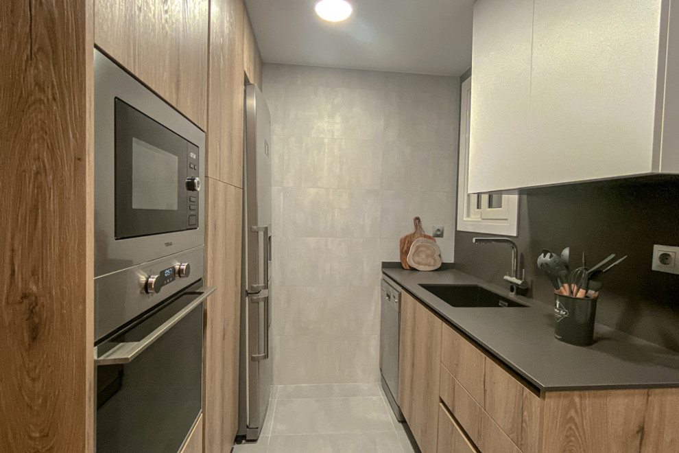 Exempel på ett litet modernt grå grått kök, med en nedsänkt diskho, släta luckor, skåp i ljust trä, bänkskiva i kvarts, grått stänkskydd, rostfria vitvaror, betonggolv, en köksö och grått golv
