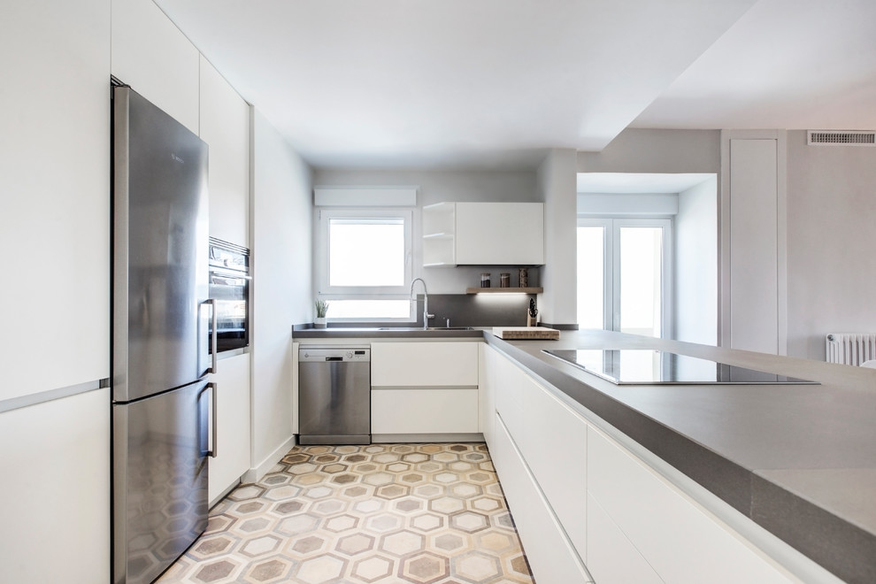 Exempel på ett skandinaviskt grå grått u-kök, med rostfria vitvaror, släta luckor, vita skåp, bänkskiva i betong, grått stänkskydd, cementgolv, en halv köksö och beiget golv