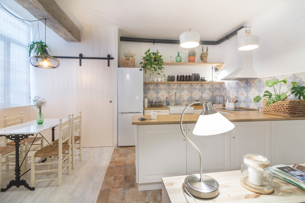 他の地域にある中くらいな北欧スタイルのおしゃれなキッチン (レイズドパネル扉のキャビネット、白いキャビネット、木材カウンター、マルチカラーのキッチンパネル、セラミックタイルのキッチンパネル、白い調理設備) の写真