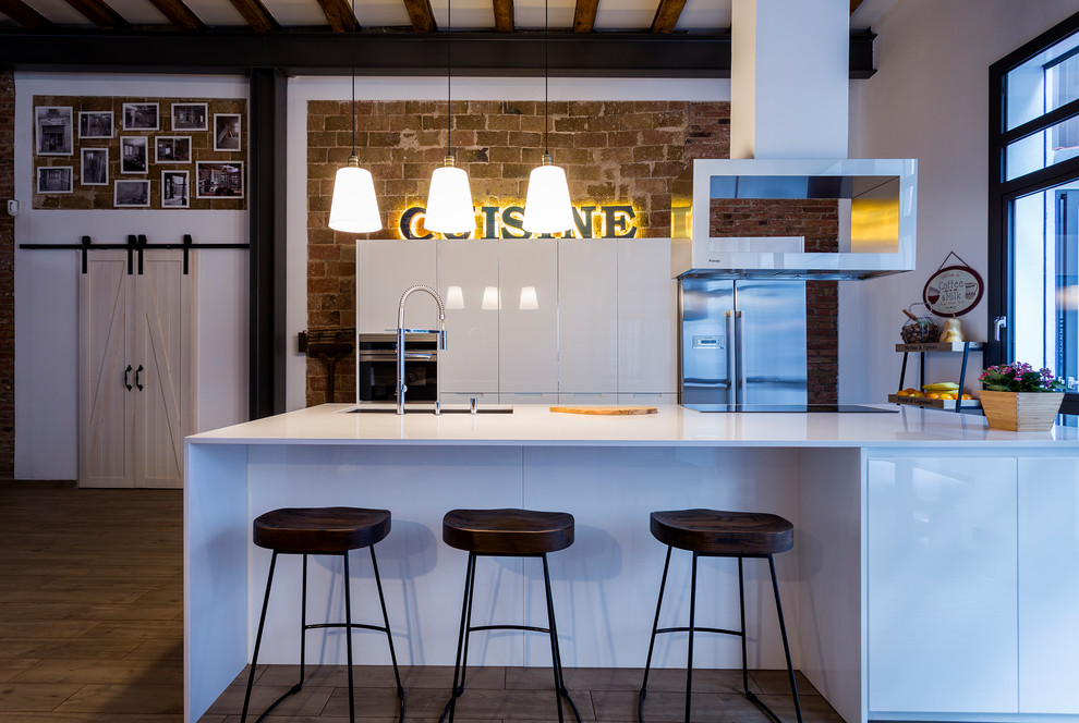 Offene, Einzeilige, Große Industrial Küche mit Doppelwaschbecken, Küchenrückwand in Weiß, Küchengeräten aus Edelstahl, braunem Holzboden und Kücheninsel in Barcelona