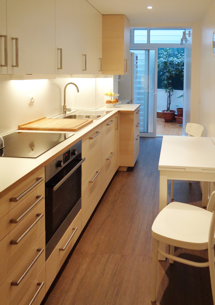 Пример оригинального дизайна: отдельная, прямая кухня среднего размера в скандинавском стиле с плоскими фасадами, светлыми деревянными фасадами и белым фартуком без острова