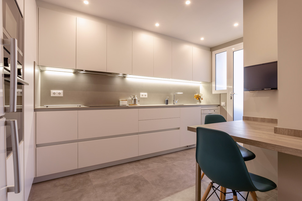 Mid-sized trendy l-shaped ceramic tile and gray floor enclosed kitchen photo in Barcelona with a single-bowl sink, flat-panel cabinets, white cabinets, beige backsplash, no island, beige countertops and black appliances