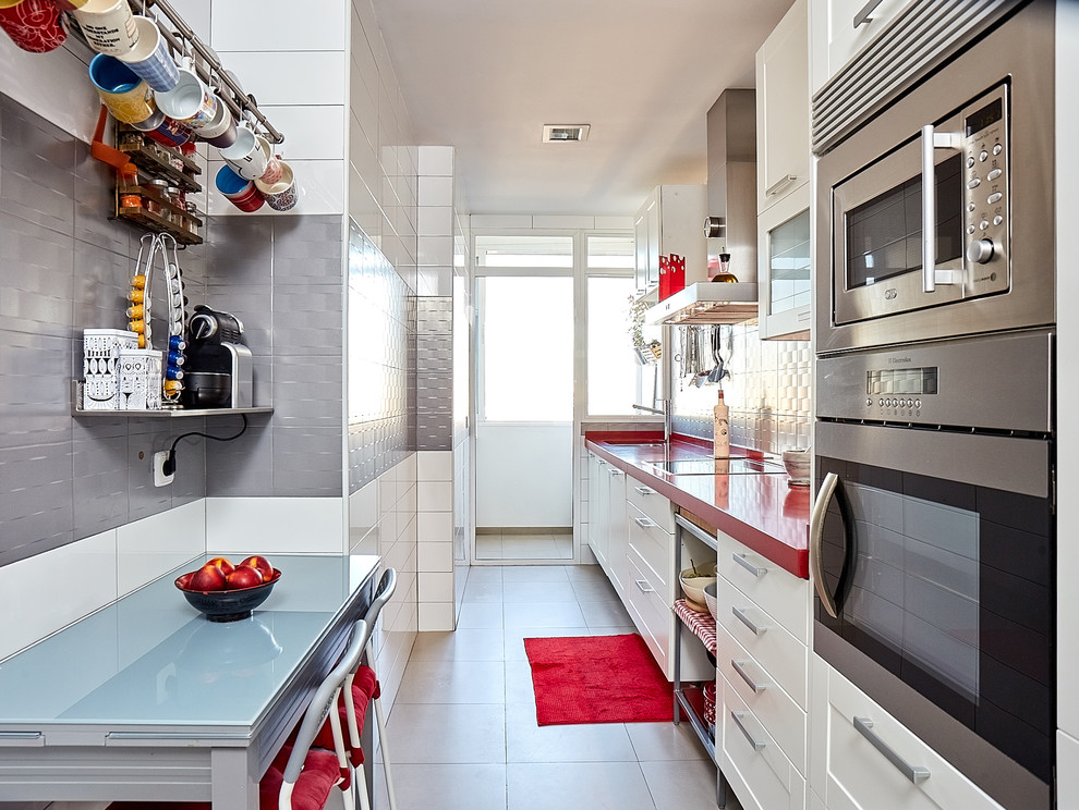 Idéer för avskilda, mellanstora funkis linjära rött kök, med en dubbel diskho, luckor med upphöjd panel, vita skåp, bänkskiva i kvarts, grått stänkskydd, stänkskydd i keramik, rostfria vitvaror, klinkergolv i porslin och grått golv