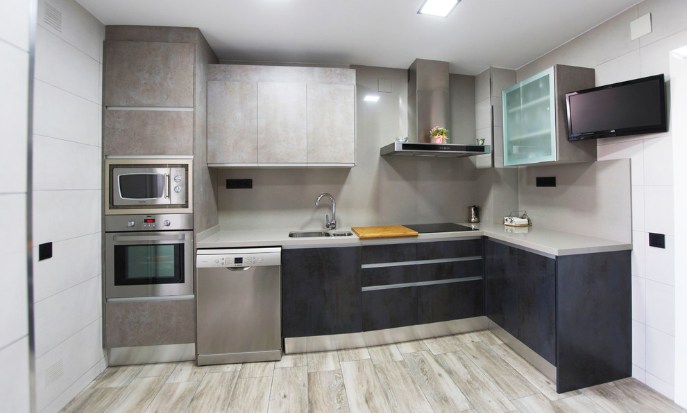 Medium sized industrial l-shaped enclosed kitchen in Barcelona with a submerged sink, flat-panel cabinets, distressed cabinets, engineered stone countertops, grey splashback, stainless steel appliances, laminate floors, no island and grey floors.