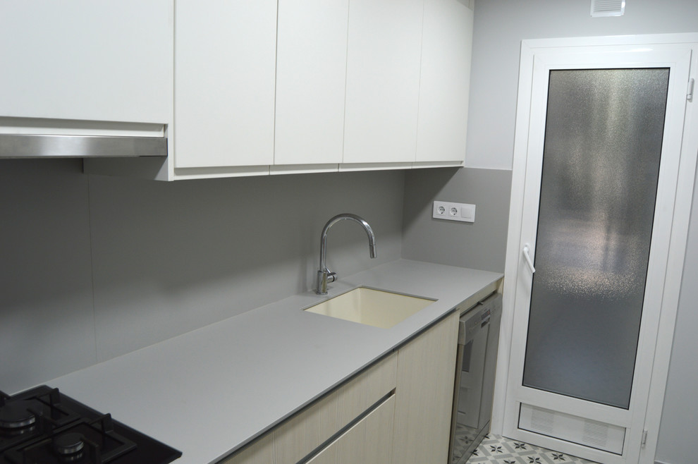 Modern inredning av ett avskilt, litet l-kök, med en undermonterad diskho, luckor med upphöjd panel, skåp i ljust trä, grått stänkskydd, rostfria vitvaror, klinkergolv i keramik och grått golv
