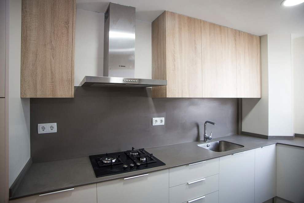 Bild på ett avskilt, mellanstort funkis u-kök, med en enkel diskho, vita skåp, grått stänkskydd, vita vitvaror och grått golv