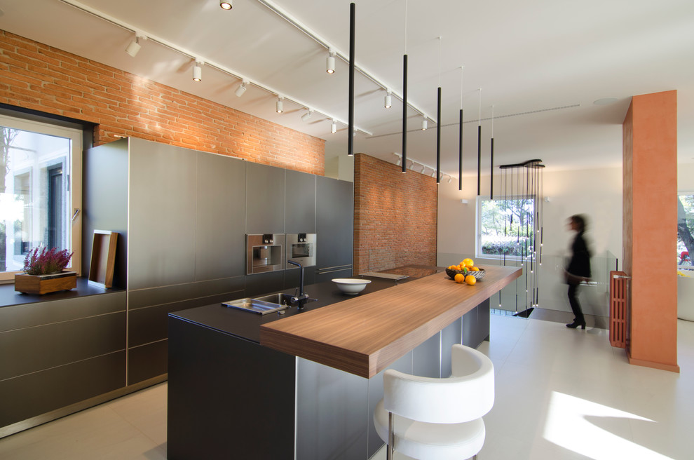 Foto de cocina lineal contemporánea grande abierta con armarios con paneles lisos, puertas de armario grises, encimera de madera, electrodomésticos de acero inoxidable y una isla