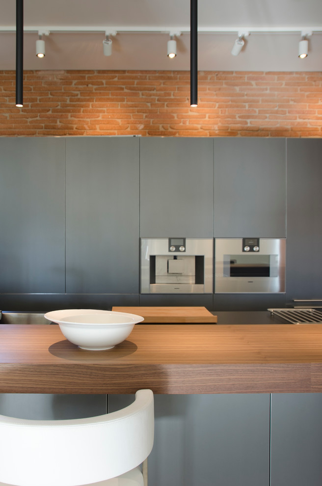 Diseño de cocina lineal contemporánea grande abierta con armarios con paneles lisos, puertas de armario grises, electrodomésticos de acero inoxidable y una isla