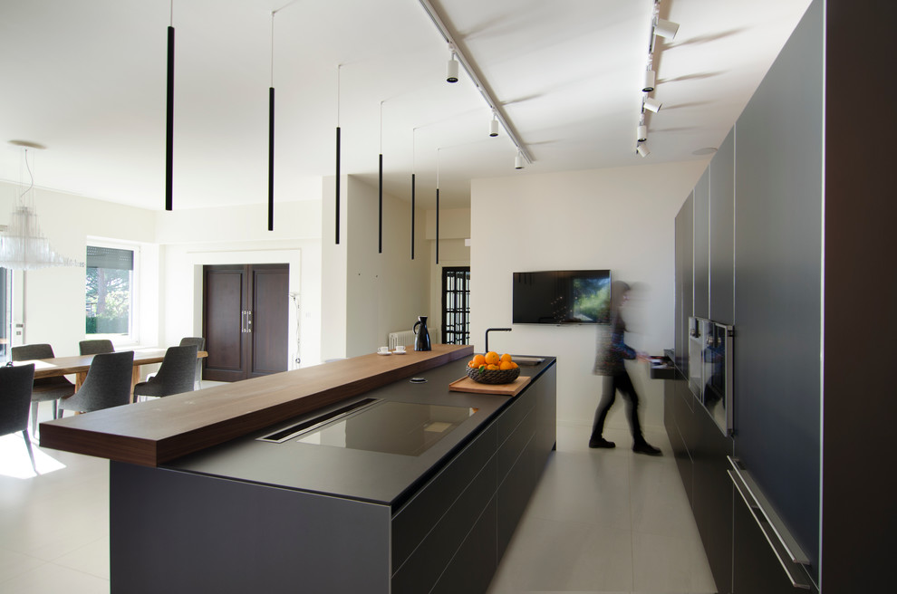 Immagine di una grande cucina minimal con ante lisce, ante grigie, elettrodomestici in acciaio inossidabile e pavimento con piastrelle in ceramica